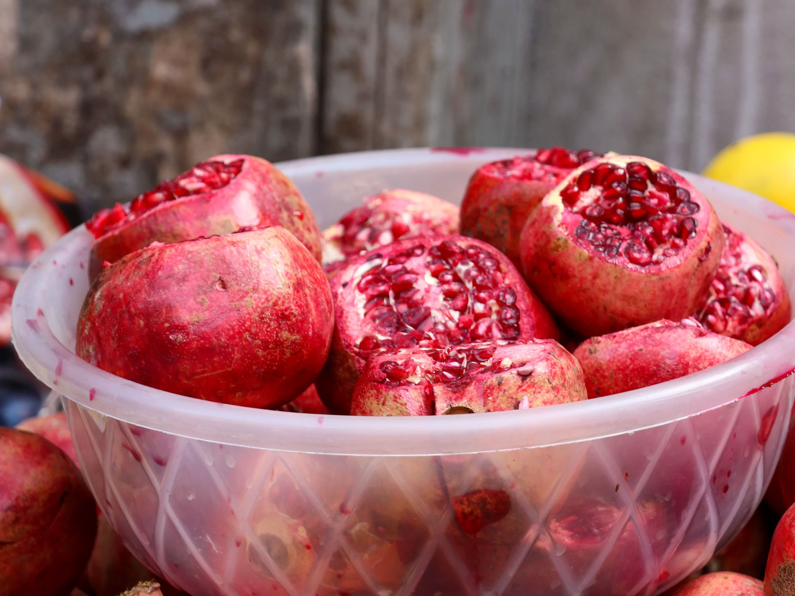 A close-up of fresh, cut pomegranates in a plastic bowl, showcasing vibrant red seeds. jigsaw puzzle